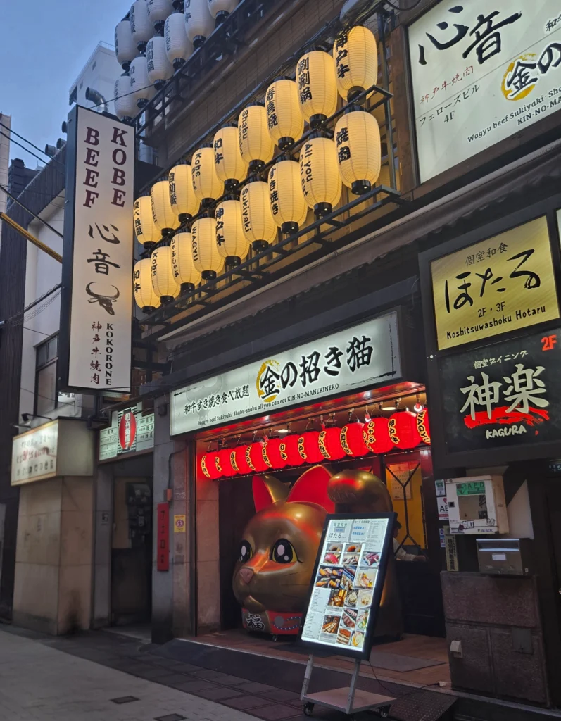 Kobe beef restaurant storefront in Japan with lanterns and giant maneki-neko cat statue